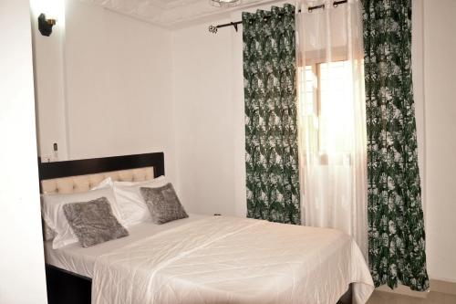 a bedroom with a bed and a window with curtains at Tulsa Home - Douala - Bonamoussadi - Wifi - Canal+ in Douala