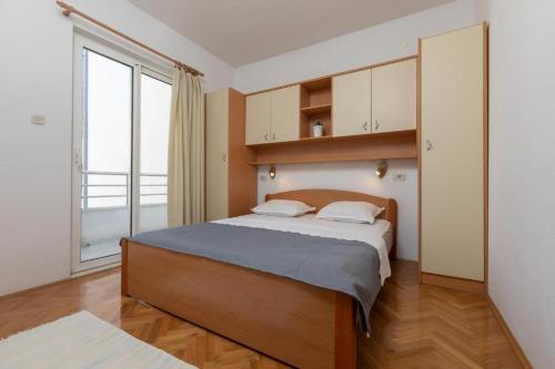 een slaapkamer met een groot bed en een groot raam bij Apartmani Vela in Tučepi