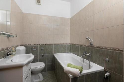 een badkamer met een bad, een toilet en een wastafel bij Apartmani Vela in Tučepi