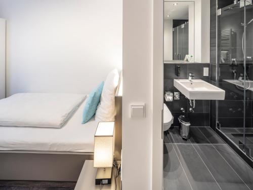 ein kleines Bad mit einem Bett und einem Waschbecken in der Unterkunft Boarding World smart Hotel in Mannheim