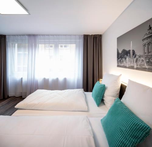 1 Schlafzimmer mit 2 weißen Betten und einem Fenster in der Unterkunft Boarding World smart Hotel in Mannheim