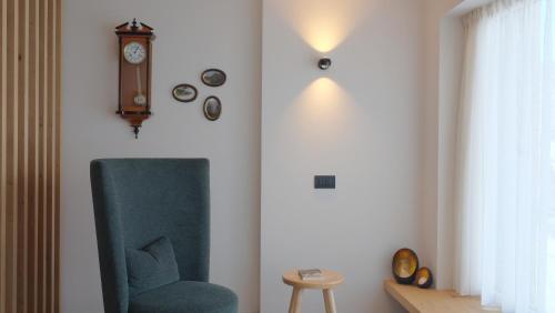a room with a chair and a clock on the wall at Runk Apartments in Siusi