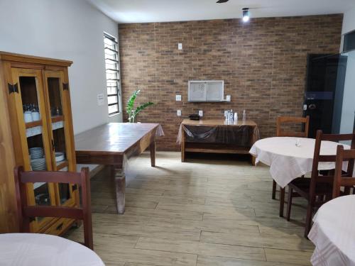 a dining room with tables and chairs and a brick wall at Hotel Village Cataguases in Cataguases