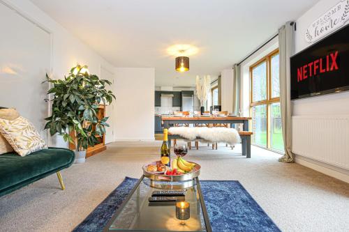 a living room with a couch and a table with a tv at Beautiful City Centre Apartment with Free Parking, Fast-Wifi, SmartTV with Netflix and Private Garden by Yoko Property in Milton Keynes