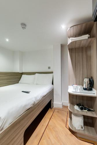 a small bedroom with a bed and a shelf at The Podworks Hotel in Liverpool