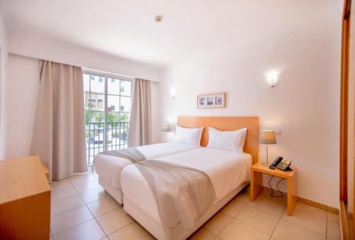 una camera con un letto bianco e una finestra di Aquamar Albufeira Aparthotel ad Albufeira