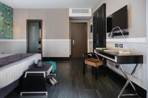 ローマにあるUnica Suites Romeのベッド、デスク、ピアノが備わるホテルルームです。