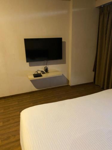 une chambre avec un lit et une télévision à écran plat dans l'établissement Weekend address homestay by shan, à Surate