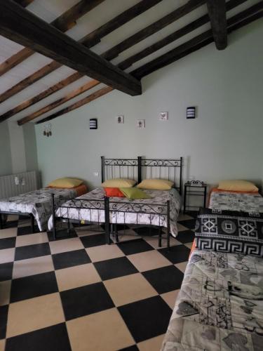 Cette chambre comprend 3 lits et un sol en damier. dans l'établissement A casa di luca, à Mediglia