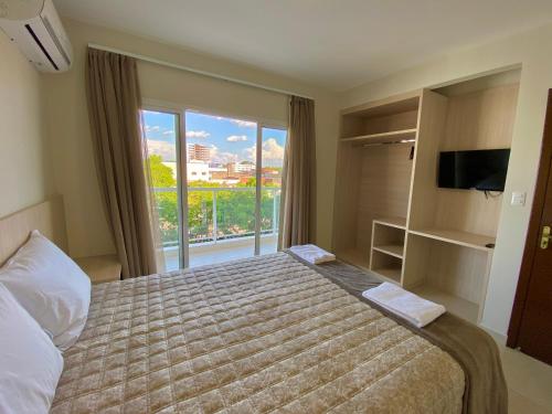 a bedroom with a bed and a large window at Residencial Shalfa in Foz do Iguaçu