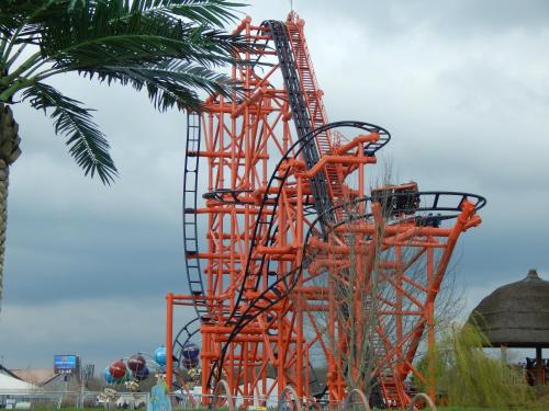 an orange roller coaster in front of a palm tree at Flamingo Land - Cedar Wood CW30 in Kirby Misperton
