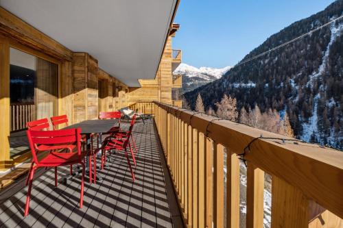 a balcony with red chairs and a table and a mountain at Chalet Les Rahâs by Mrs Miggins in Grimentz