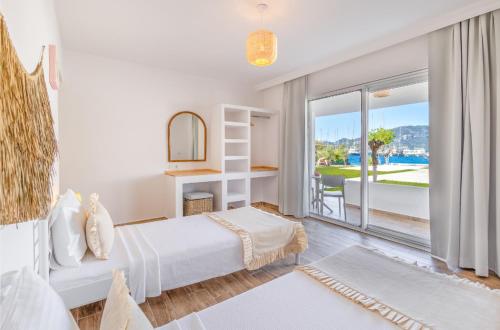 a white bedroom with a bed and a large window at selimiye base in Marmaris