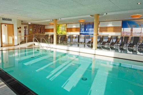 a large swimming pool with chairs in a building at Landrefugium Obermüller 4,5 Sterne in Untergriesbach