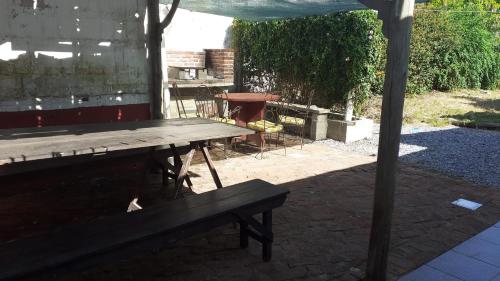 una mesa de picnic de madera y un banco en el patio trasero en LA CASA DE LOS OLMITOS, en Punta del Este