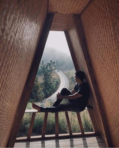 a woman sitting on a bench looking out of a window at Monsonkeang Camping view ม่อนสันเกี๋ยง in Mae Chaem