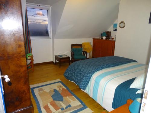 a bedroom with a bed and a chair and a window at Chambres d'hôtes de Kermerrien in Porspoder