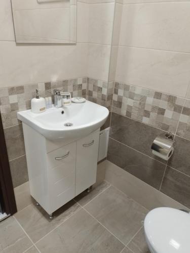 a bathroom with a white sink and a toilet at Апартамент Рая 2 in Dobrich