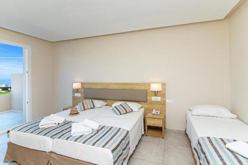 a bedroom with two beds and a balcony at Theo Star Beach Hotel in Malia