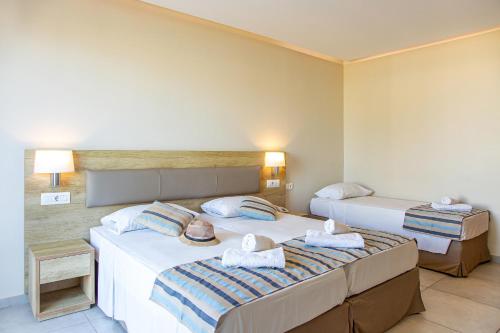 two beds in a hotel room with towels on them at Theo Star Beach Hotel in Malia