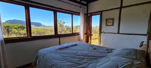 a bedroom with a bed in a room with windows at Weekend Yoga Resort Paraíso dos Pândavas in Alto Paraíso de Goiás
