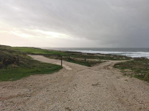 a dirt road near the ocean on a cloudy day at Villa Lala in Amoreira