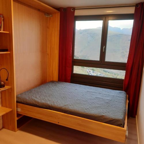 a small bed in a room with a window at Studio pied des pistes saint lary in Saint-Lary-Soulan