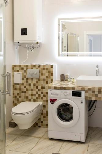 a bathroom with a toilet and a washing machine at Sun apartments in Kyiv