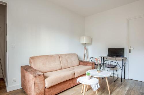 - un salon avec un canapé brun et 2 tables dans l'établissement Appartement Ocre - Welkeys, à Bagnolet