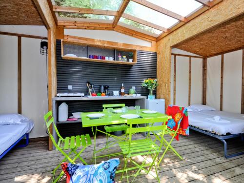 Habitación con una mesa verde y sillas en el patio. en Camping Emeraude en Saint-Briac-sur-Mer