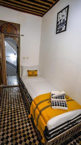 a bedroom with two beds and a checkered floor at Riad Green House in Fès