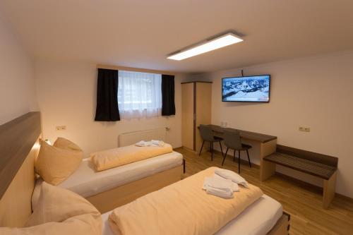 a hotel room with two beds and a desk at Gästehaus Ingeborg in Saalbach-Hinterglemm