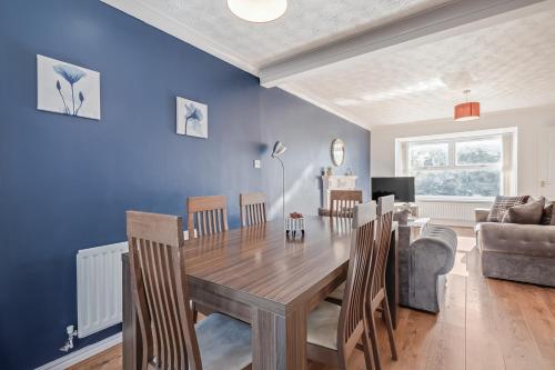 a dining room with blue walls and a table and chairs at Spacious and Comfortable Home near Fosse Park in Kirby Muxloe