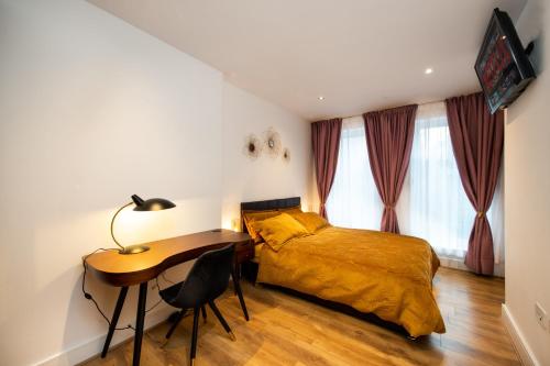Schlafzimmer mit einem Bett und einem Schreibtisch sowie einem Bett und Vorhängen in der Unterkunft London Nino Apartments in London