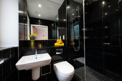 y baño con aseo, lavabo y ducha. en London Nino Apartments, en Londres