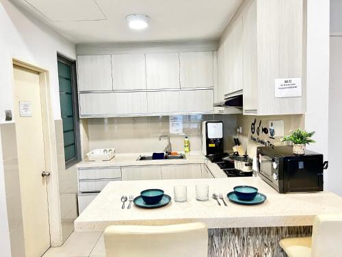 a kitchen with white cabinets and blue dishes on a counter at AJ Suites @ Loft Imago KK in Kota Kinabalu
