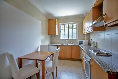 a small kitchen with a table and chairs and a sink at Aquamar Albufeira Aparthotel in Albufeira