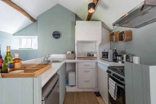 una cucina con armadi bianchi e piano cottura di Talliers Cottage - Characterful & Central a Cirencester