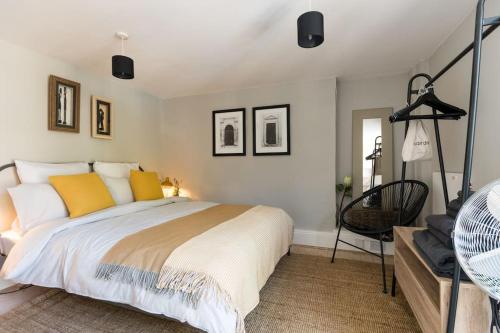 1 dormitorio con 1 cama grande con almohadas amarillas en Talliers Cottage - Characterful & Central en Cirencester