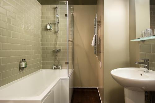 a bathroom with a tub and a sink and a shower at The Angel Inn - The Inn Collection Group in Bowness-on-Windermere