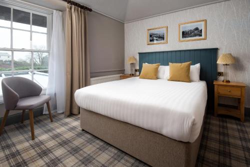 a bedroom with a bed and a chair and a window at The Angel Inn - The Inn Collection Group in Bowness-on-Windermere