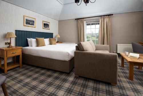 a hotel room with a bed and a couch and a chair at The Angel Inn - The Inn Collection Group in Bowness-on-Windermere