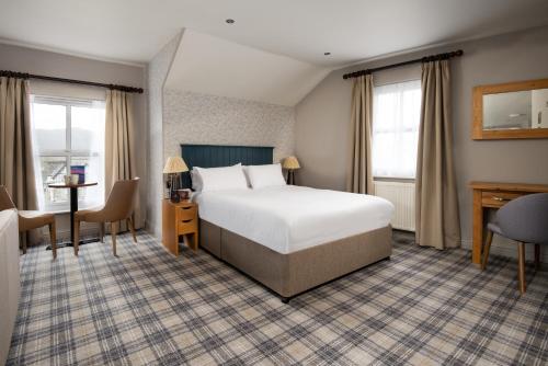 a hotel room with a bed and a desk and windows at The Angel Inn - The Inn Collection Group in Bowness-on-Windermere