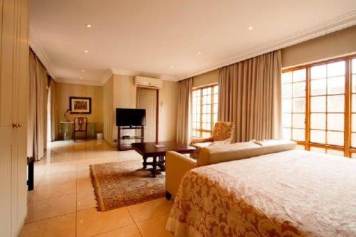 a bedroom with a bed and a couch and a table at Birdwood Boutique Estate in Pretoria