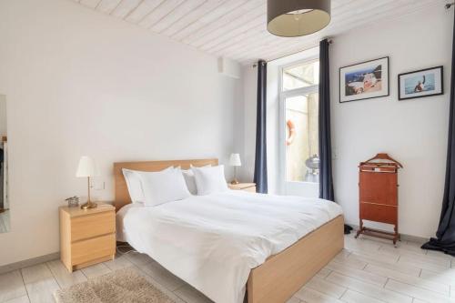 - une chambre avec un grand lit blanc et une fenêtre dans l'établissement Le Hublot - Meublé Tourisme Classé 3 étoiles, à Cherbourg en Cotentin