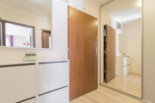 a bathroom with a wooden door and a mirror at Sudety Park MyWeek in Polanica-Zdrój