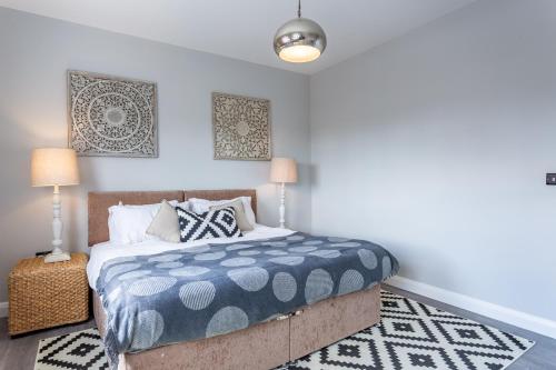 a bedroom with a bed with a blue and white comforter at 2 Bedroom Apartments with Sofa bed in Southend in Southend-on-Sea