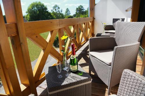 a balcony with two chairs and a table with wine bottles at FeWo-Zimmer-Auszeit in Drahnsdorf