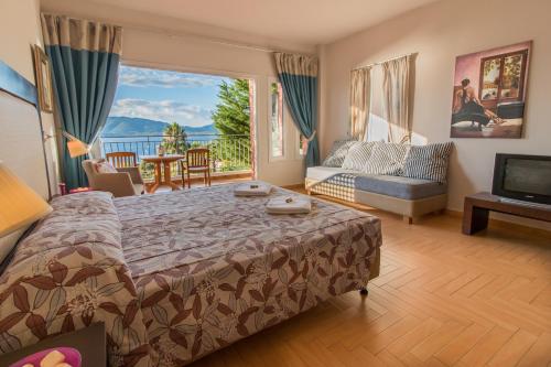 Schlafzimmer mit einem Bett und Blick auf einen Balkon in der Unterkunft Thalassa Hotel in Palairos