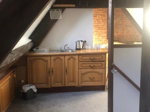 an attic kitchen with wooden cabinets and a sink at The Ilchester Arms Hotel in Ilchester
